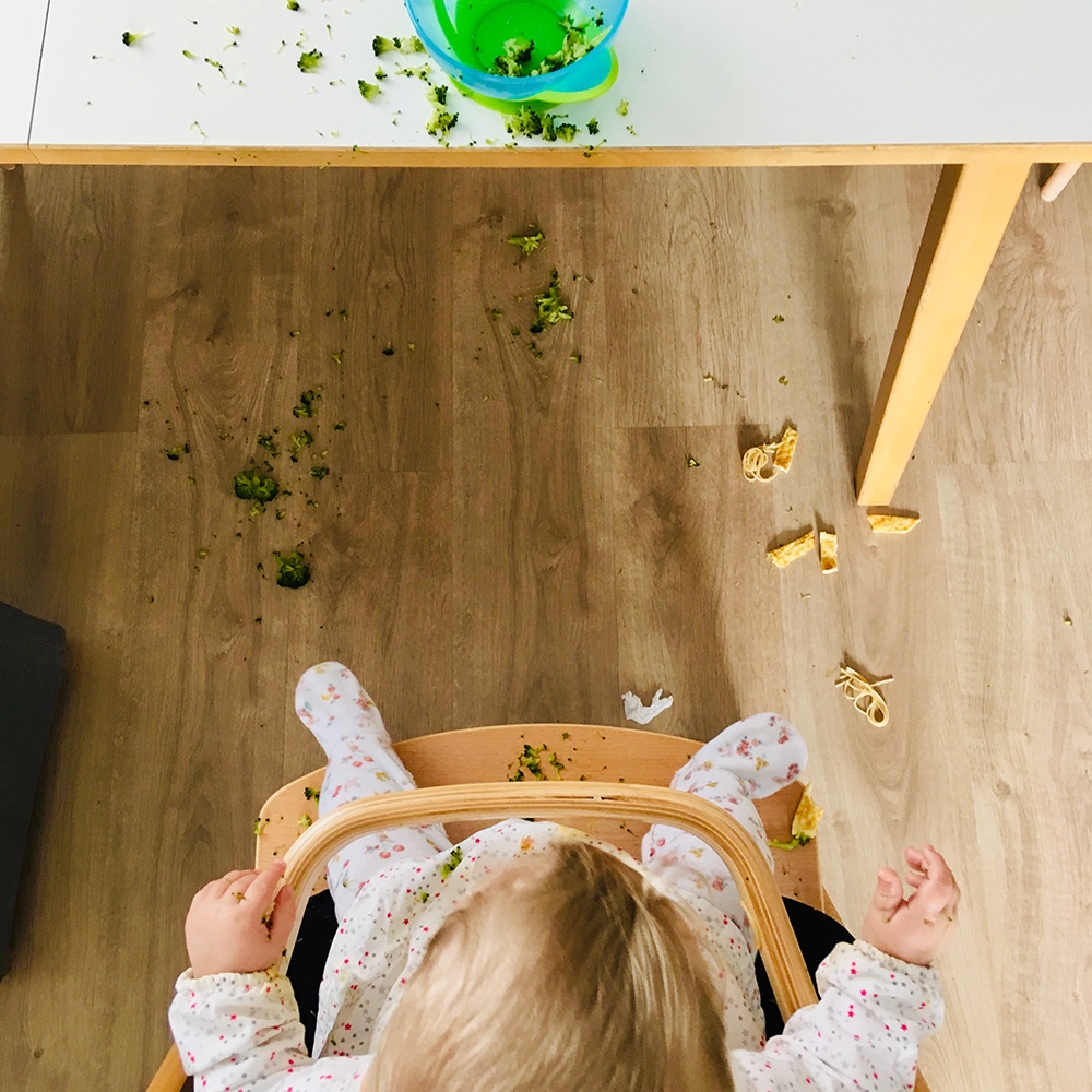 Bebé mirando el suelo sucio tras una comida con BLW. 